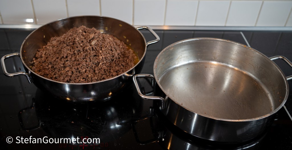 A pot of coarsely ground beef is shown on a stovetop, with another empty pot beside it.