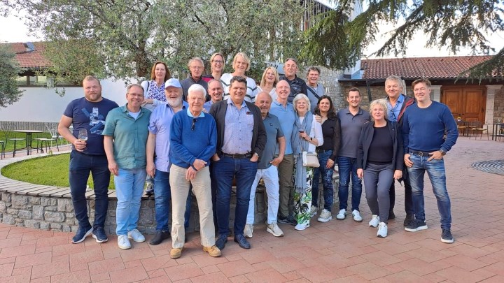 A group photo of wine enthusiasts gathered in a picturesque outdoor setting, smiling and posing together, showcasing a blend of camaraderie and appreciation for wine culture.