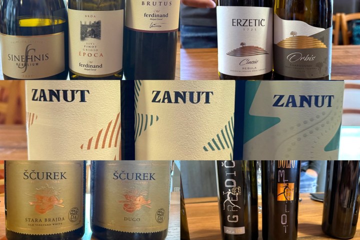 A selection of wine bottles displayed on a wooden table, featuring labels from various wineries including Ferdinands, Erzetič, Zanut, and Ščurek.