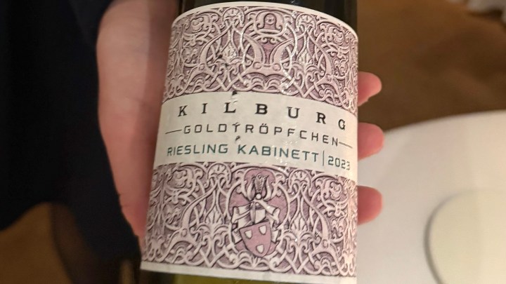 A close-up of a Riesling Kabinett wine bottle labeled 'Kilburg Goldtröpfchen 2023', featuring intricate decorative design on the label.