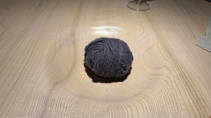 A gray ball of wool placed in the center of a wooden table, symbolizing the chef's motto about cooking.