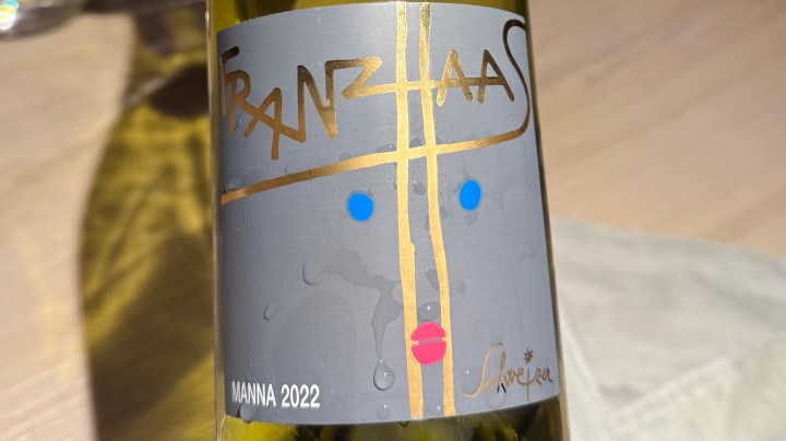 Close-up of a bottle label for Franz Haas Manna 2022 wine, featuring a colorful design with gold accents.