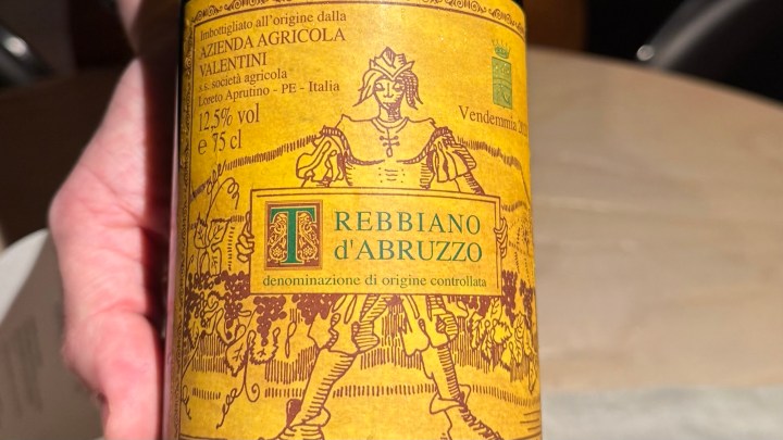A close-up of a Trebbiano d'Abruzzo wine bottle from Azienda Agricola Valentini, featuring a vintage label with a depiction of a historical figure and details about the wine's origin and alcohol content.