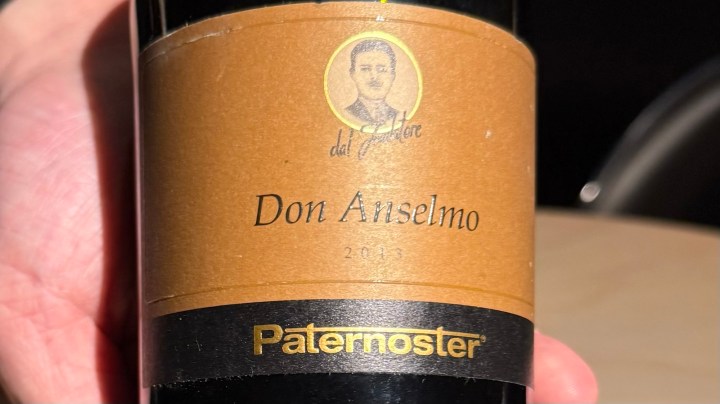 Close-up of a wine bottle labeled 'Don Anselmo 2013' by Paternoster, held in a hand.