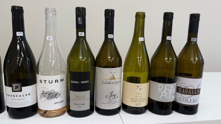 A display of seven bottles of Collio wines, including Pinot Grigio and others, arranged on a white table.