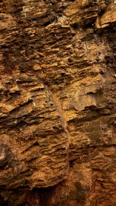 Close-up of layered rock displaying rich earthy tones and textures, characteristic of the ponca soil found in the Collio wine region.