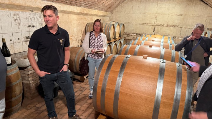 Wine maker Miha Ritonja explains the wine-making process in a cellar filled with large wooden barrels.