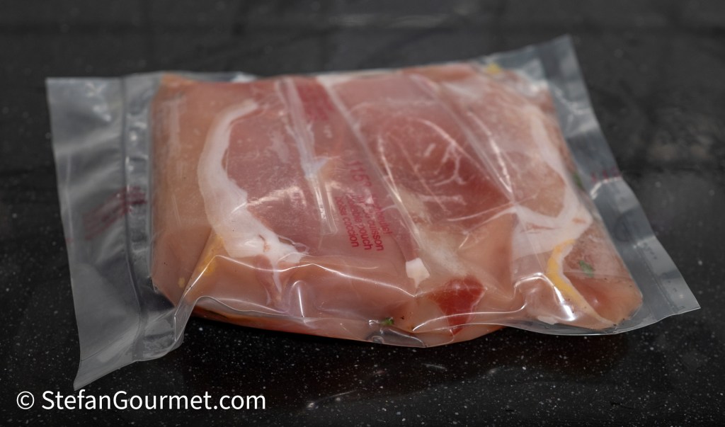 Vacuum-sealed guinea fowl breast fillets wrapped in prosciutto, ready for sous vide cooking.