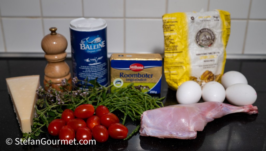 Ingredients for cooking, including rabbit legs, cherry tomatoes, samphire, eggs, butter, Parmesan cheese, and flour, arranged on a kitchen counter.