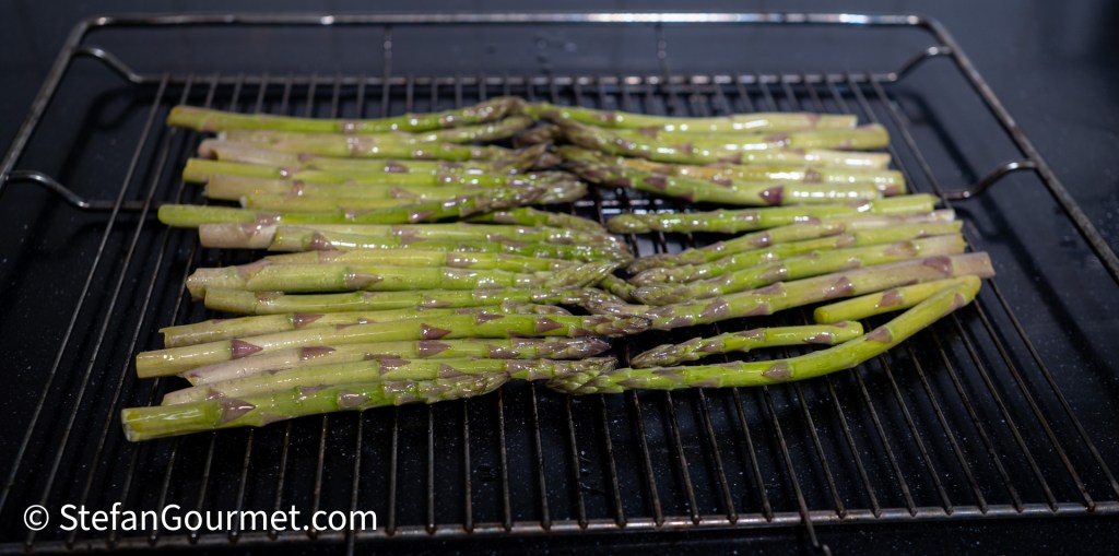 Fresh green asparagus arranged on a grill, ready to be cooked.