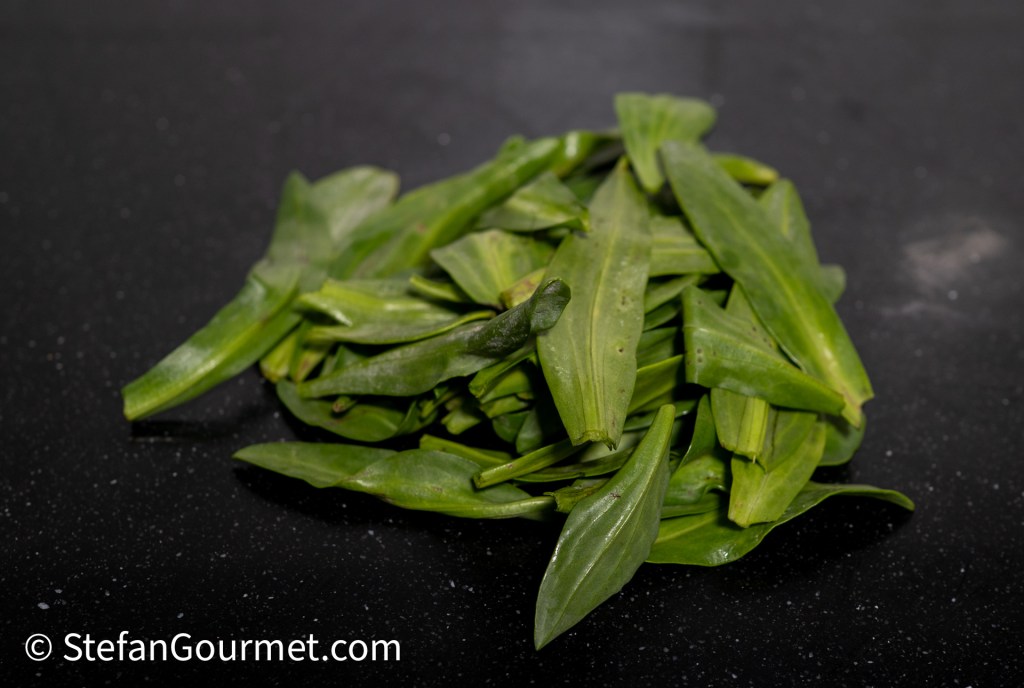 A pile of fresh sea lavender leaves on a black countertop.