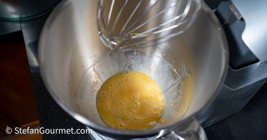 Bowl with beaten eggs and a whisk, indicating preparation for a cooking process.