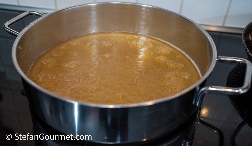 A pot of bubbling rabbit stock on a stovetop.