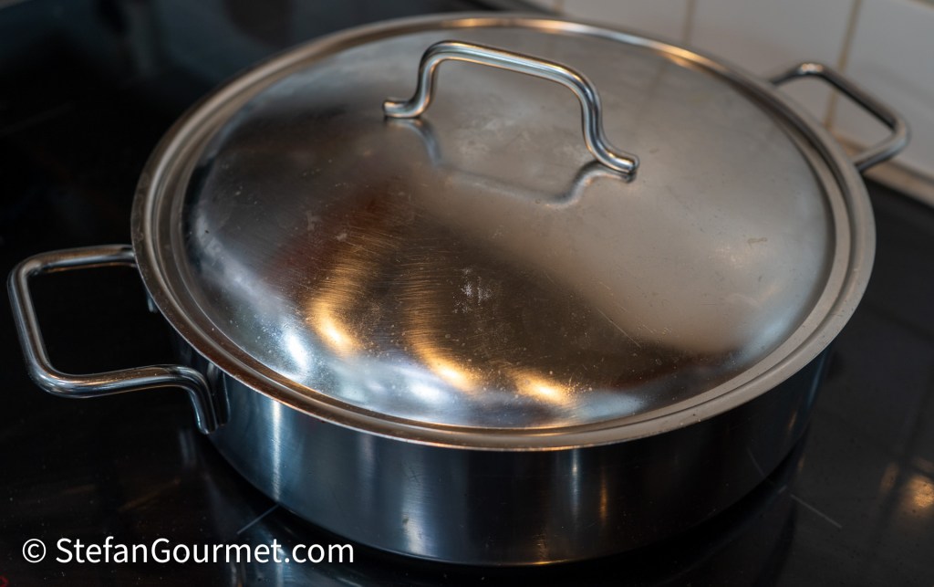 A stainless steel pot with a lid, resting on a stovetop.