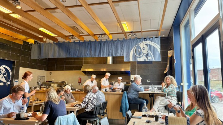 Interior of Hokkai Kitchen restaurant, featuring Japanese decor and customers dining while chefs work in the background.