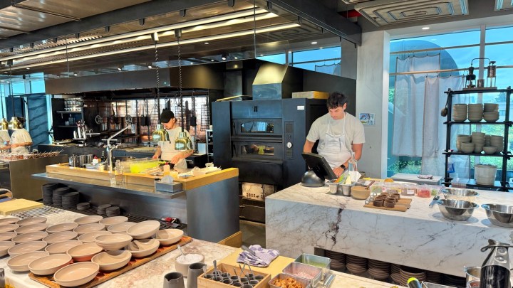 The open kitchen at Wils restaurant featuring chefs at work, with a charcoal fire and various cooking equipment visible.