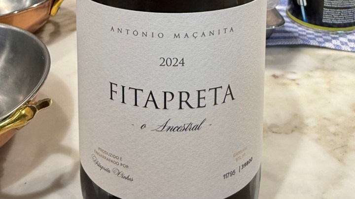 Close-up of a wine bottle labeled 'FITAPRETA o Ancestral' from 2024, produced by António Maçanita. The bottle is placed on a marble surface surrounded by kitchen items.