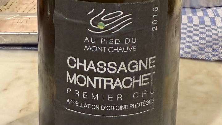 A close-up of a wine bottle labeled 'Chassagne Montrachet Premier Cru 2016', showcasing the intricate design on the label.