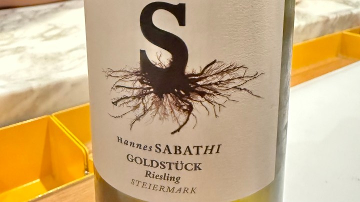 Close-up of a wine bottle label featuring 'Hannes Sabathi Goldstück Riesling Steiermark' with a distinctive root graphic.