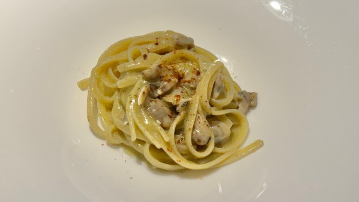 A plate of linguine pasta served with clams, garnished with a sprinkle of spices.