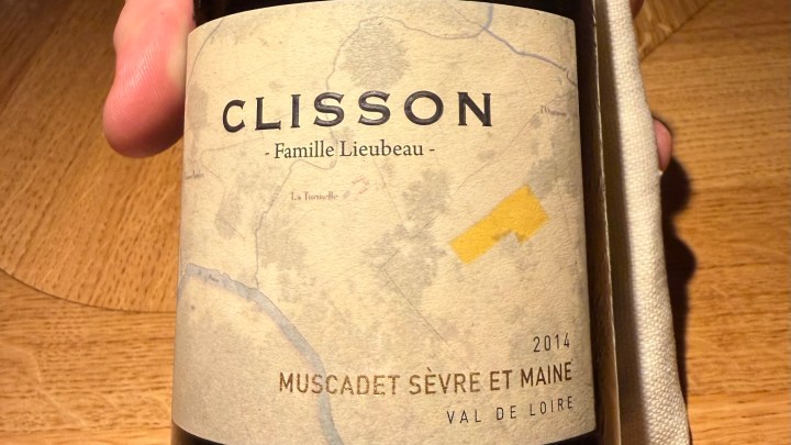 Close-up of a bottle of 2014 Clisson Muscadet Sèvre et Maine from the Loire Valley, held in hand.
