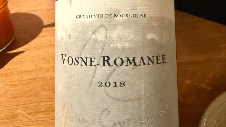 A close-up image of a wine bottle labeled 'Vosne-Romanée 2018' with 'Grand Vin de Bourgogne' printed above the label.