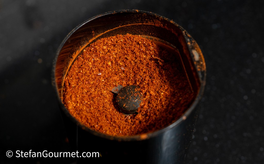 Close-up view of red chili powder in a spice grinder.