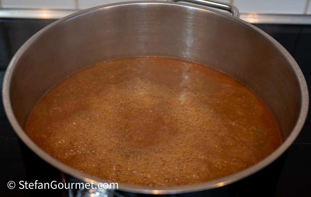 A large pot filled with simmering broth, showing bubbles on the surface.