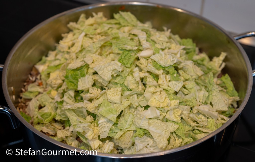 A large pot filled with shredded savoy cabbage in preparation for risotto.