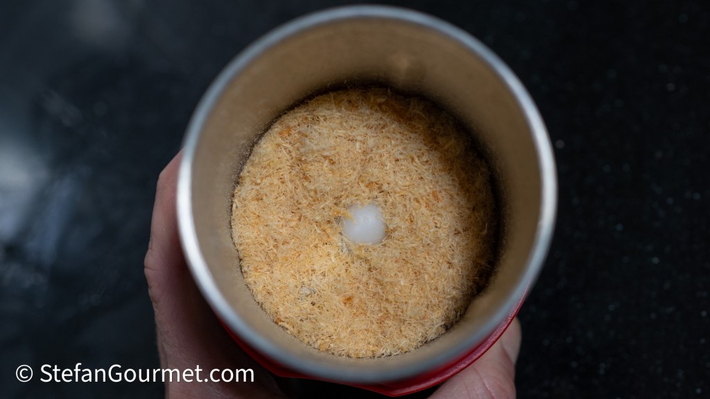 Close-up of ground dried shrimp in a spice grinder, showcasing a fine powder texture.