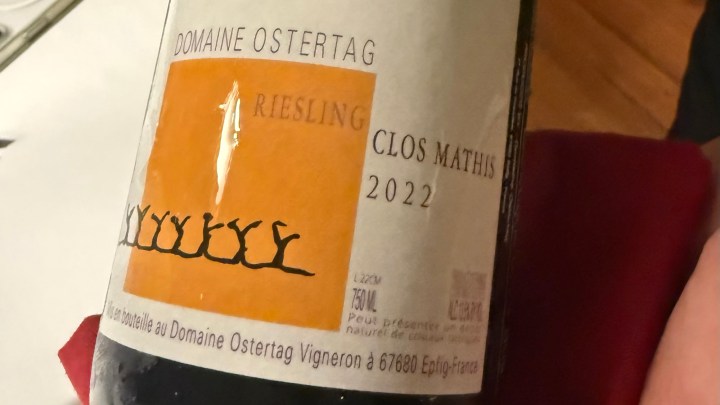 A close-up of a wine bottle labeled 'Domaine Ostertag Riesling Clos Mathis 2022', showcasing its colorful design and details.