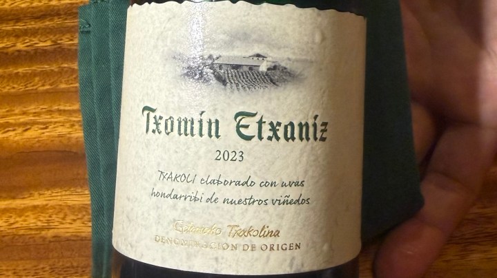 Label of Txomin Etxaniz 2023 Txakoli wine, featuring a vineyard illustration and text in Spanish detailing the origin and type of wine.