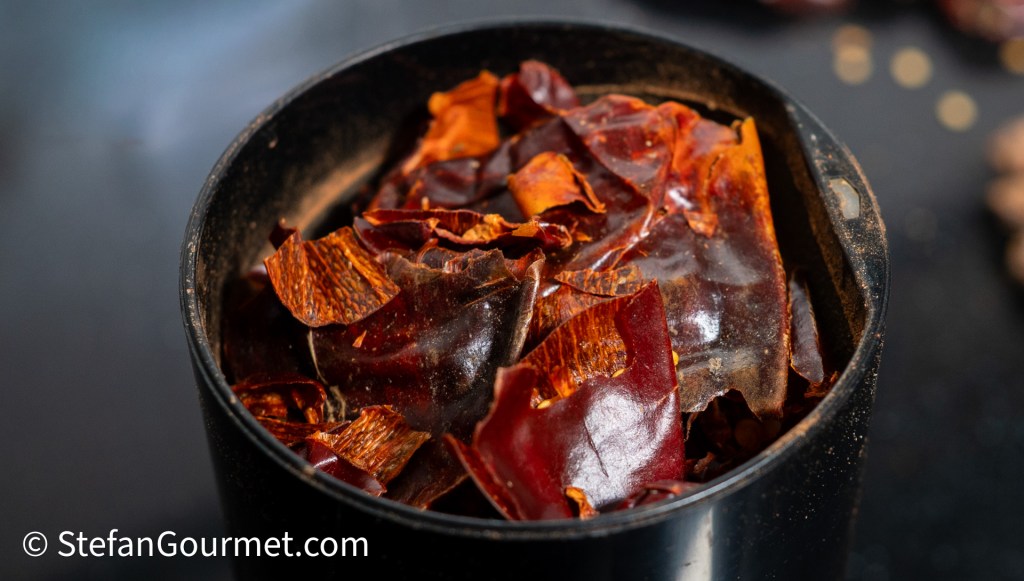 Close-up of dried red chilies stacked in a spice grinder, ready for grinding into powder.