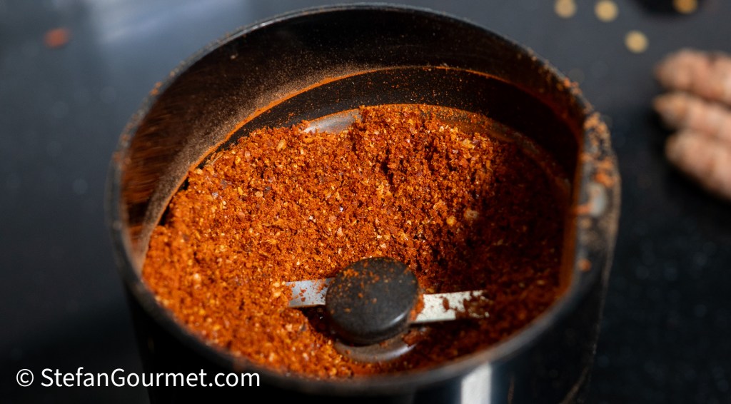 Close-up of freshly ground colorful curry powder in a spice grinder.