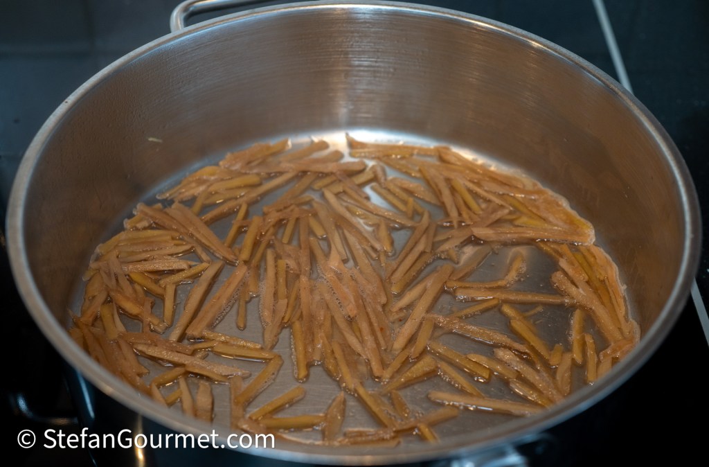Thinly sliced ginger simmering in a pot with water.