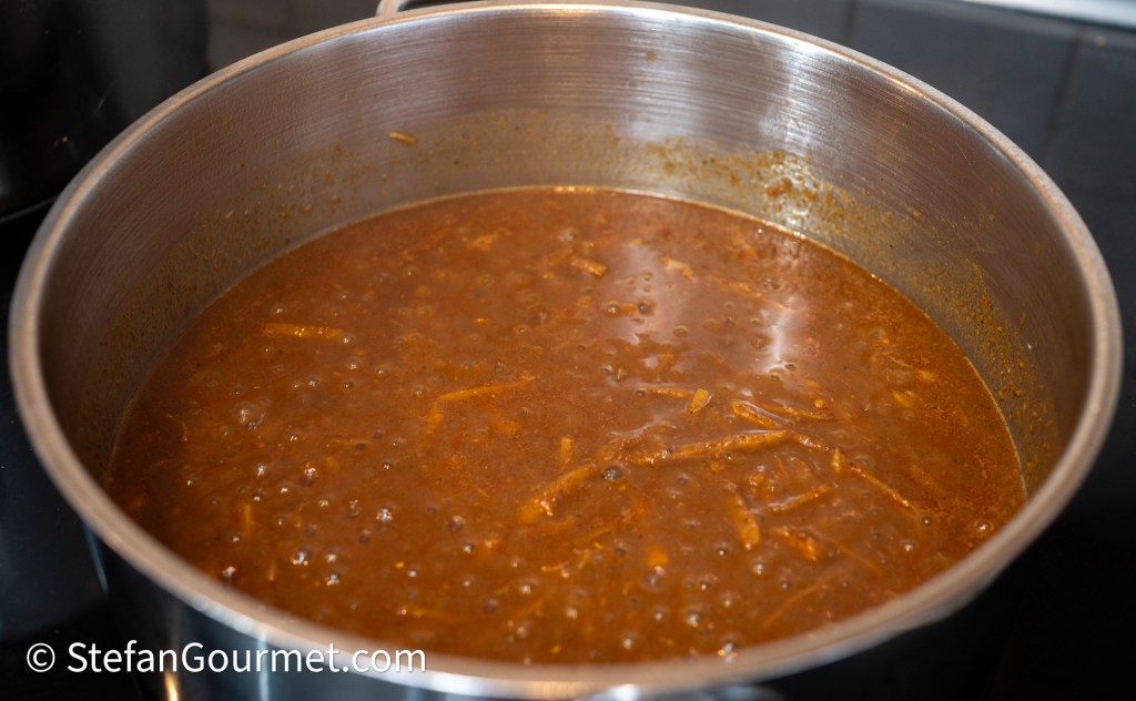 A pot of Gaeng Hung Lay curry simmering, showcasing a rich, brown sauce with visible spices and ingredients.