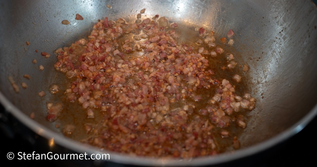 Pan with finely chopped pancetta cooking in oil until golden and crispy.