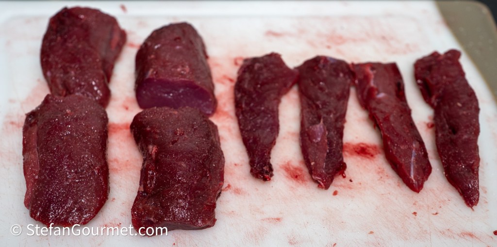 Sliced hare fillets of varying sizes arranged on a white cutting board.