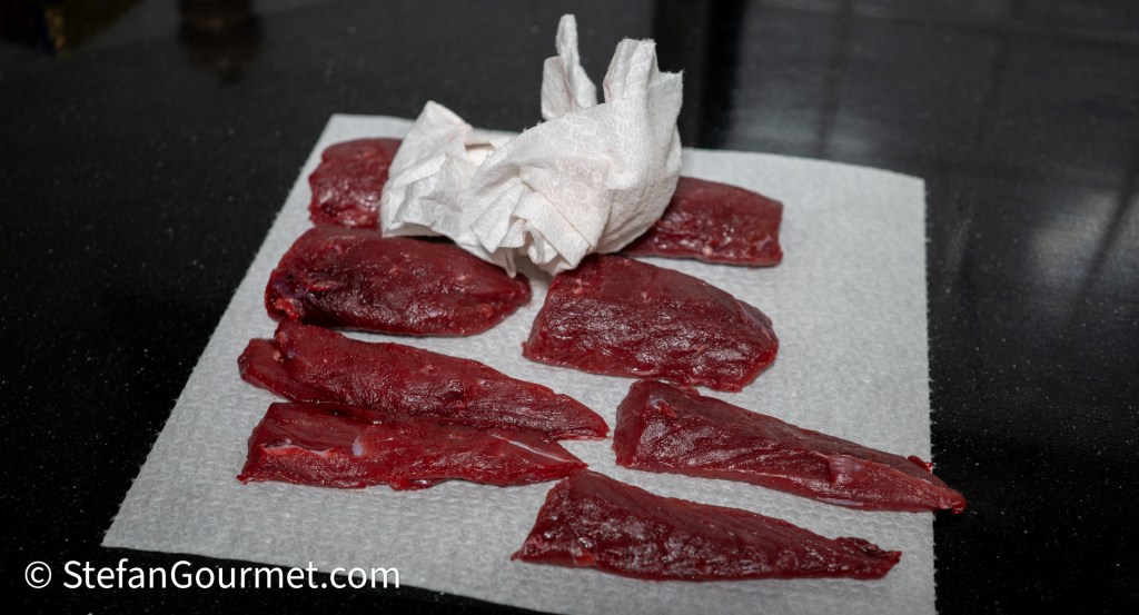 Slices of hare meat arranged on a paper towel, with a few pieces overlapping and a crumpled paper towel in the background.