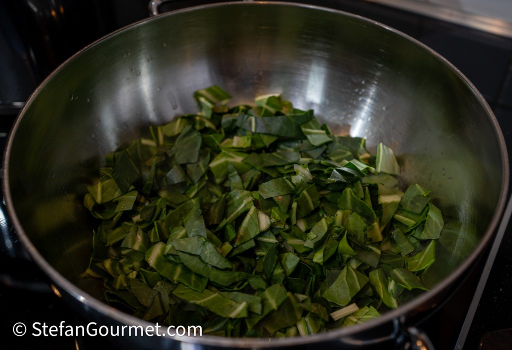 Chopped chard leaves in a large stainless steel pot, ready for cooking.
