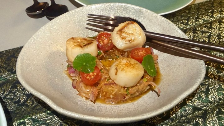 A plate of _yum som-o hoi shell_, featuring Thai pomelo salad, pan-seared scallops, cherry tomatoes, and garnished with mint leaves.