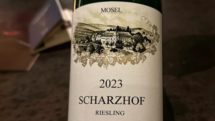 A close-up of the 2023 Scharzhof Riesling wine bottle, featuring an illustrated label with the vineyard and detailed text.