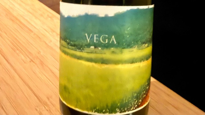 Label of Vega sake featuring a green field and hills in the background.