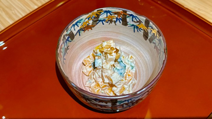 A beautifully crafted bowl filled with a colorful dessert made from various ingredients, presenting an elegant presentation on a red decorative tray.