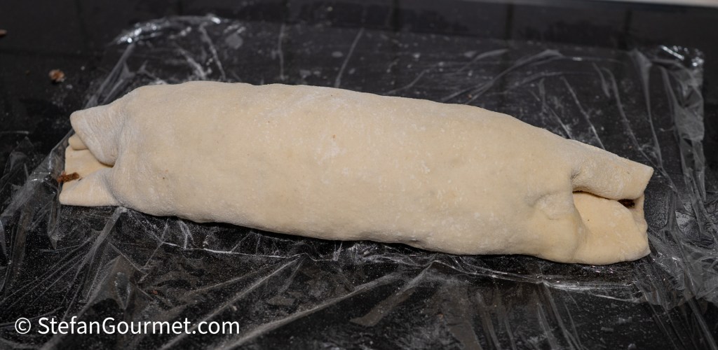 A rolled piece of dough resting on plastic wrap, ready for baking.