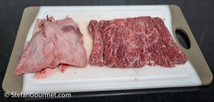 Raw meat portions on a cutting board, featuring a fatty piece on the left and a marbled piece on the right.