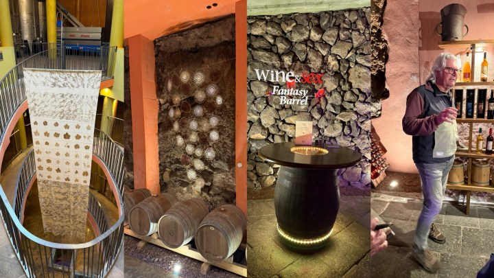 Interior view of a wine cellar featuring a decorative pillar, stacked wine barrels, and a display area with stone walls and lighting.