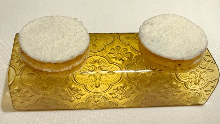 Two round, white dessert pieces sitting on an ornate golden serving tray.