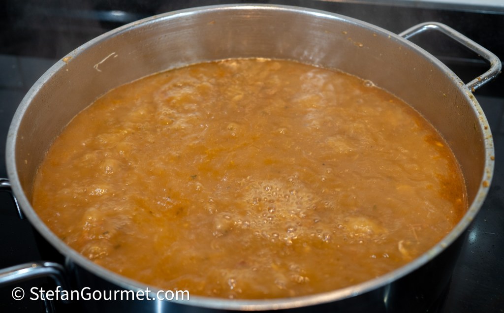 A large pot of simmering soup with bubbling liquid and steam rising from the surface.