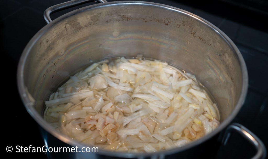A pot with sliced vegetables submerged in water, simmering on a stovetop.